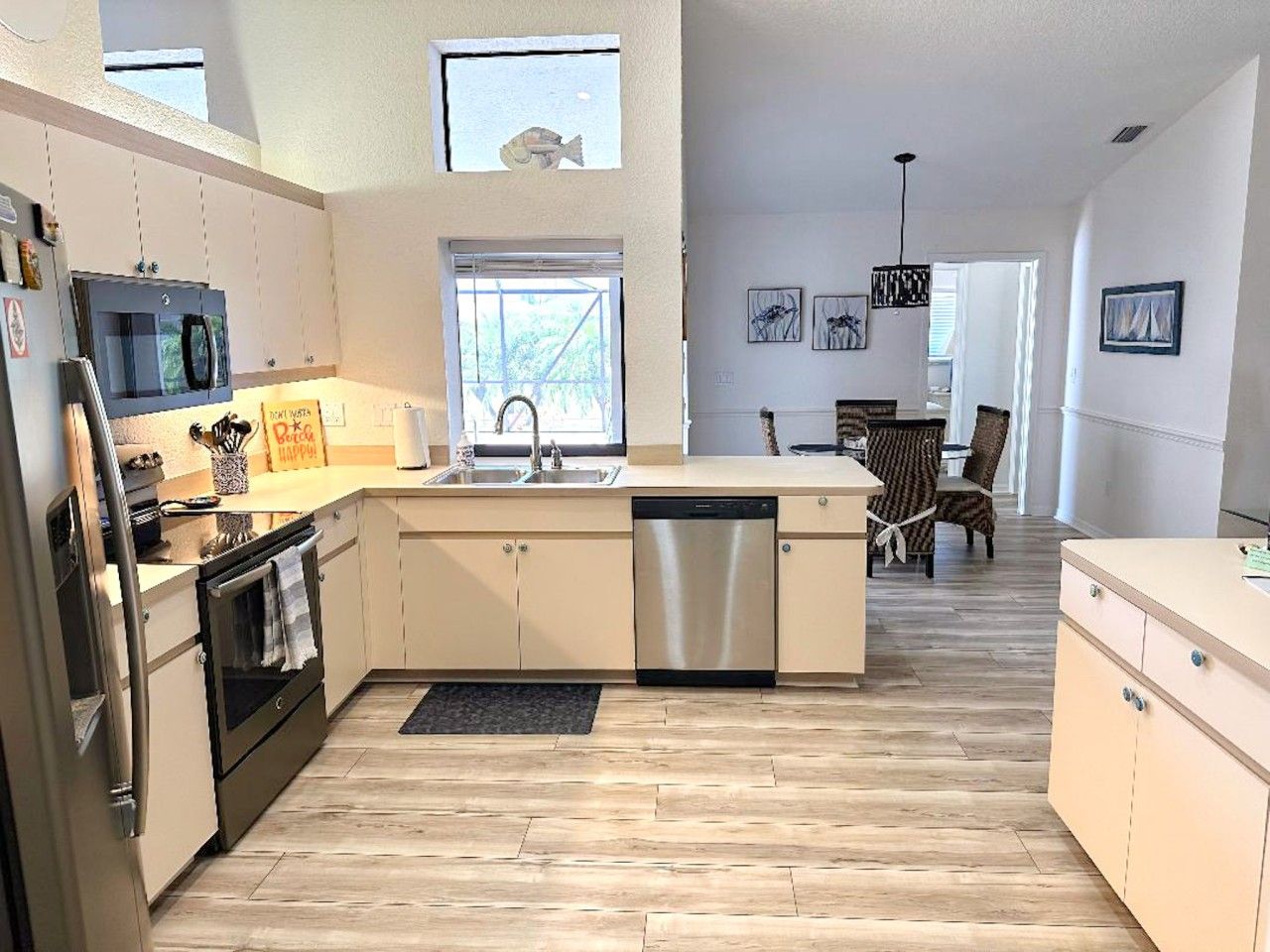 A modern kitchen with a dishwasher, oven, and microwave. There is a dining area with a table and chairs.