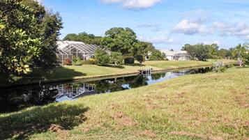 A greenhouse structure, a water body, and a grassy area with trees.