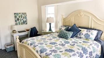 A bedroom with a bed, bedside tables, a lamp, a window, and a wall decoration.