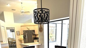A dining area with a glass-top table, wicker chairs, and a black pendant light. - Gulf Tranquility in Rotonda West (Rotonda West)