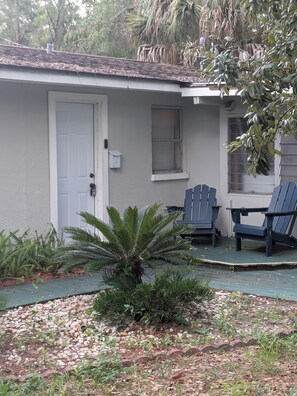 A house with a front door, a window with shutters, and two Adirondack chairs on a porch. - Enjoyable Queen bdrm space charming Crystal River Close to everything  SNOWBIRDS (Crystal River)