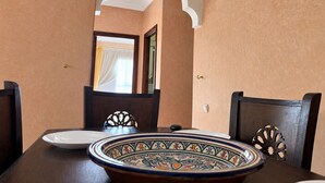 Zona de menjador amb taula preparada per a dues persones, amb un plat decoratiu i un plat blanc.