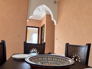 Uma área de refeições com uma mesa posta para dois, com um prato decorativo e um prato branco.