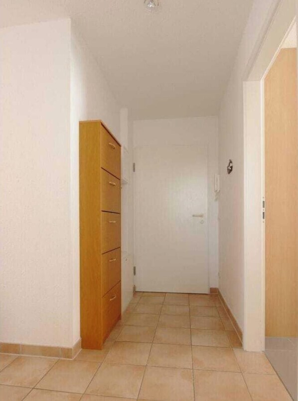 A hallway with a wooden wardrobe, a white door, and tiled flooring. - Residence on the Beach 4-59 (Zingst)