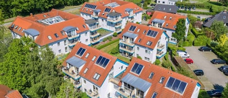 A residential area with multiple two-story houses featuring red-tiled roofs and solar panels.
