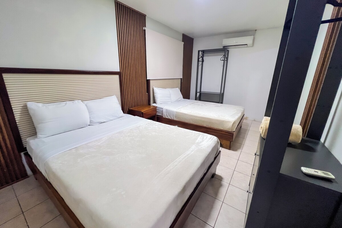 A hotel room with two beds, a wooden headboard, a wardrobe, and a mirror.