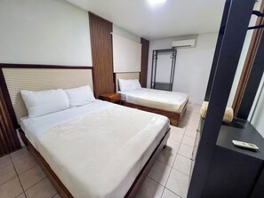 A hotel room with two beds, a wooden headboard, a wardrobe, and a mirror. - Toucan Arenal Lodge (La Fortuna)