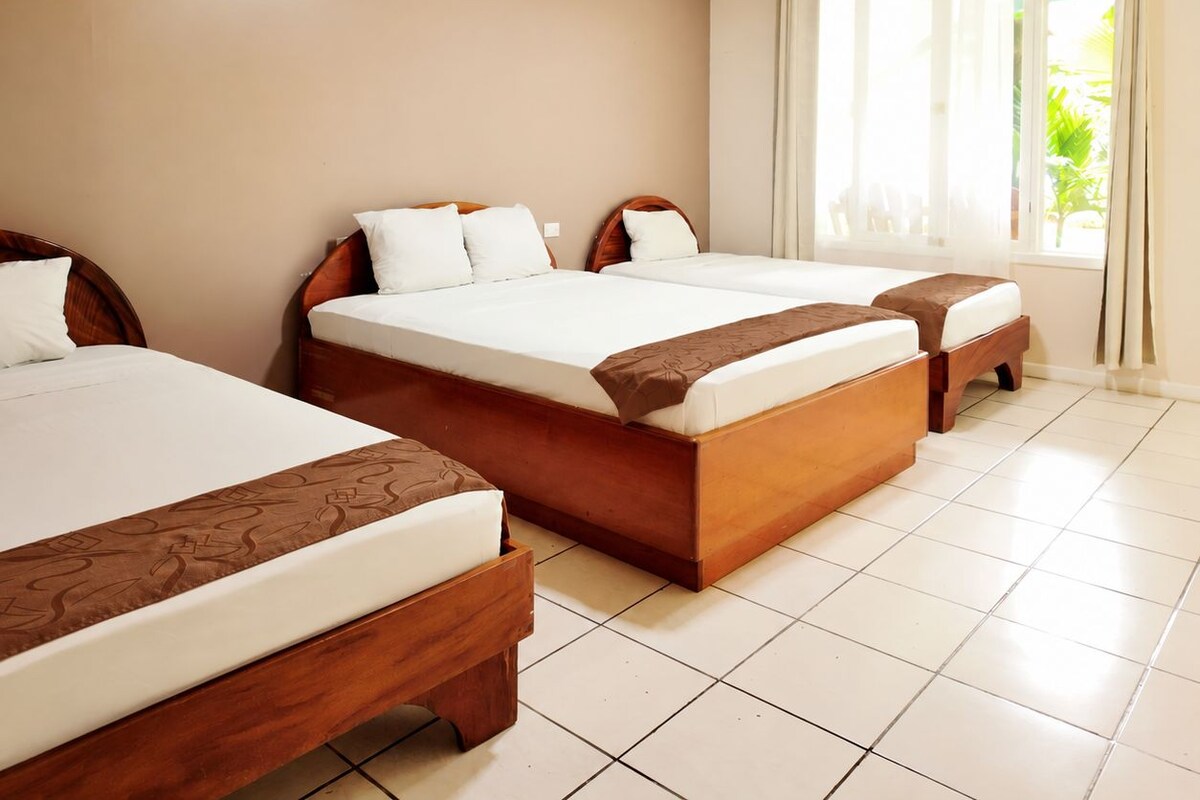 A hotel room with two beds, a window with curtains, and a tiled floor.