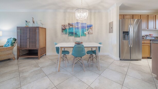 Uma cozinha moderna com mesa de jantar, cadeiras, lustre e geladeira.