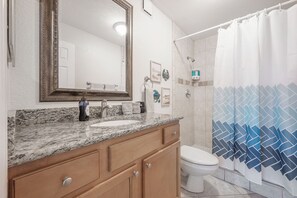 Une salle de bain avec un lavabo en marbre, des toilettes et un rideau de douche.
