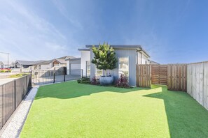 A residential area with modern houses, a well-maintained lawn, and a wooden fence.