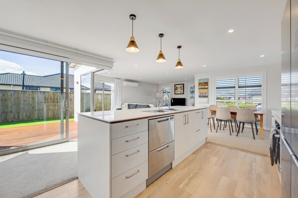 A modern kitchen with a large island, stainless steel appliances, and pendant lighting.