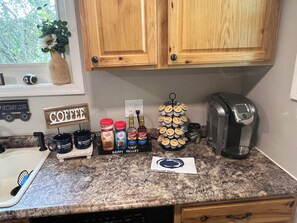 Eine Küchenarbeitsplatte mit Zubehör für die Kaffeezubereitung, einer Kaffeetasse, einem Kaffeepress und einem Schild mit der Aufschrift Kaffee.