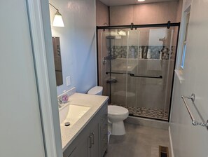 Ein modernes Badezimmer mit einer Duschkabine, einer Toilette und einem Waschbecken mit Seifenspender.