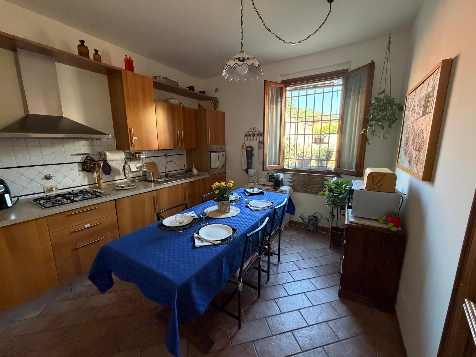 Une cuisine avec des meubles de rangement en bois, une cuisinière à gaz et une table à manger pour quatre personnes.