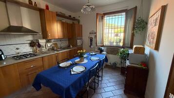 Une cuisine avec des meubles de rangement en bois, une cuisinière à gaz et une table à manger pour quatre personnes.