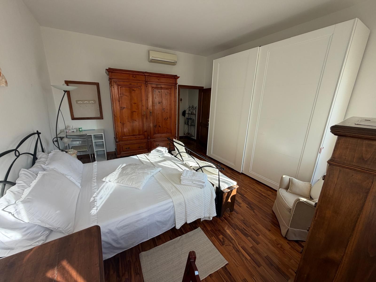 Une chambre à coucher avec un lit, une armoire en bois, un bureau avec une lampe et une chaise.