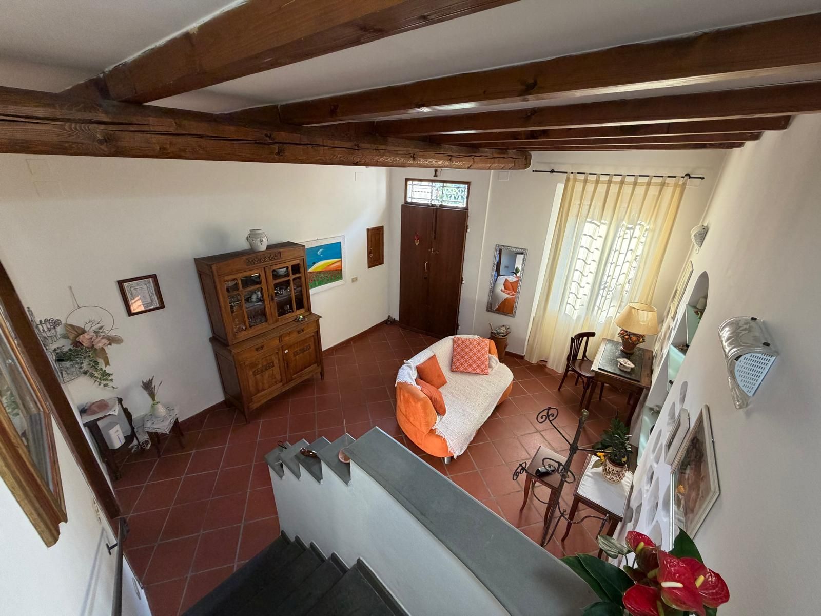 A room with a bed, a wooden cabinet, a dining table, and a staircase.