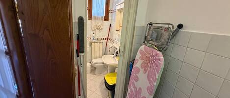 Un baño pequeño con inodoro, lavamanos y zona de ducha.