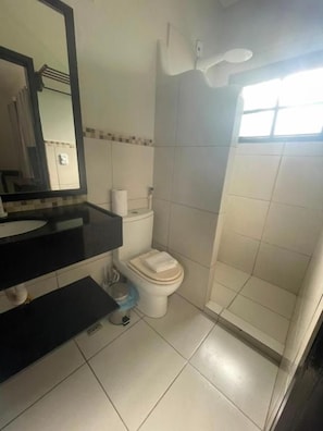 Un baño con inodoro, lavabo, espejo y ducha.