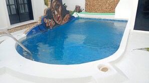 A swimming pool with a clear blue water surface, a ladder, and a partial view of a wall with a textured surface. - Vila Verissimo  (Jericoacoara)
