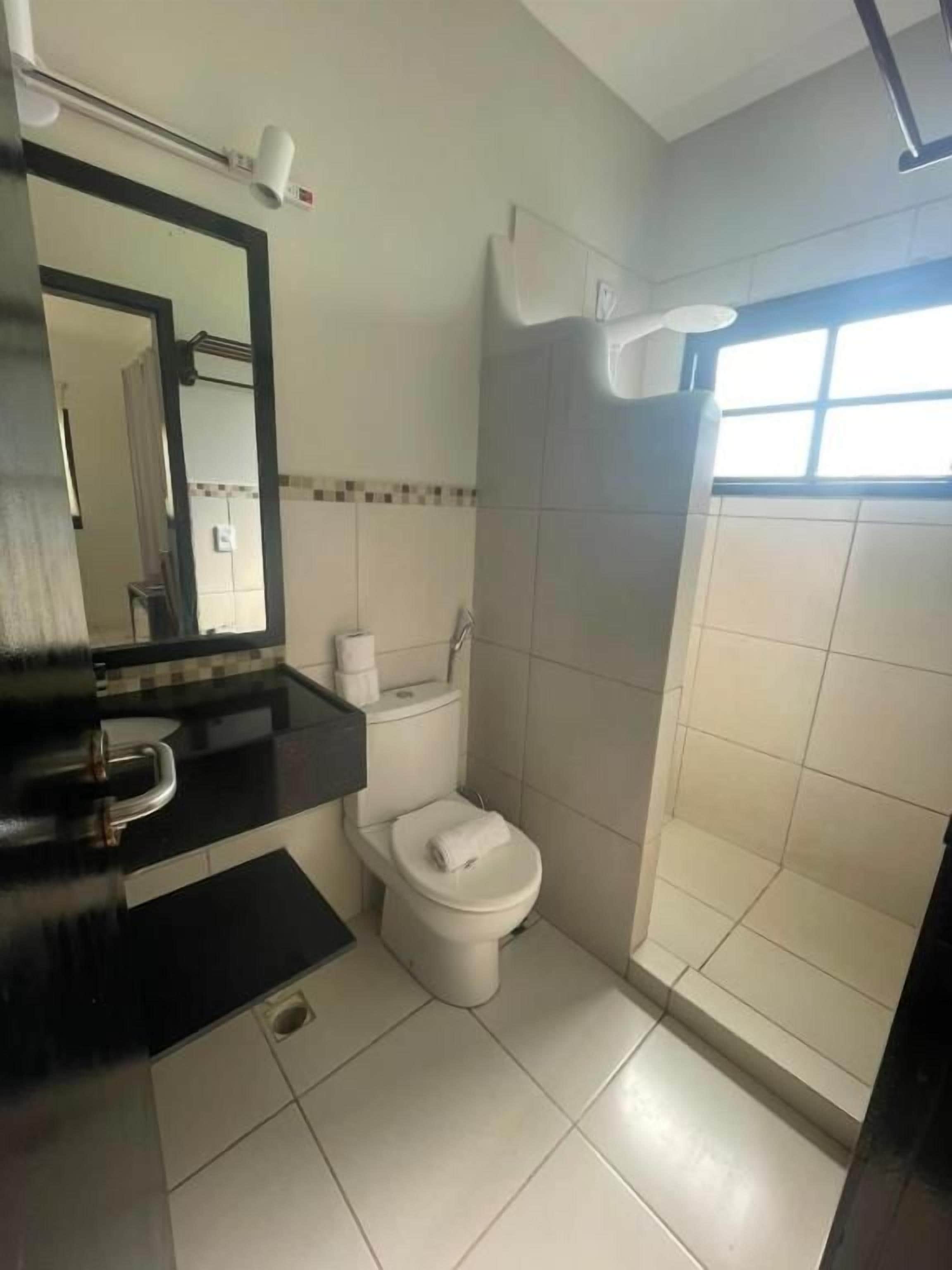 Un baño con inodoro, lavamanos, espejo y cabina de ducha.
