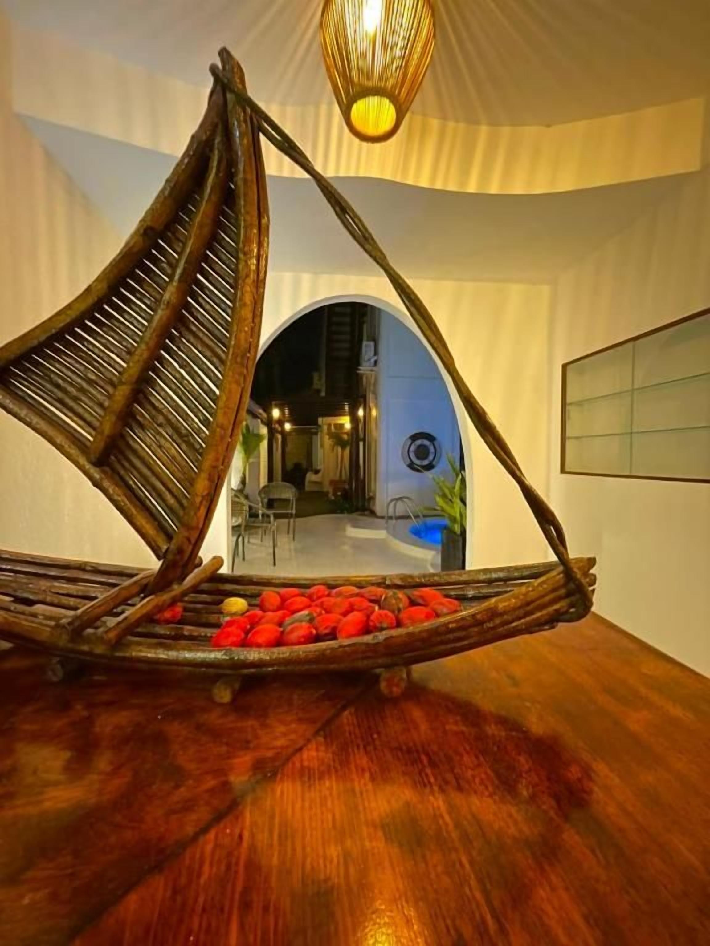A room with a unique hanging chair filled with red objects, a wooden floor, and a ceiling light fixture.