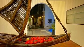 A room with a unique hanging chair filled with red objects, a wooden floor, and a ceiling light fixture.