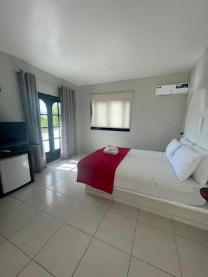 Una habitación de hotel con una cama, un escritorio, una ventana y un equipo de aire acondicionado.