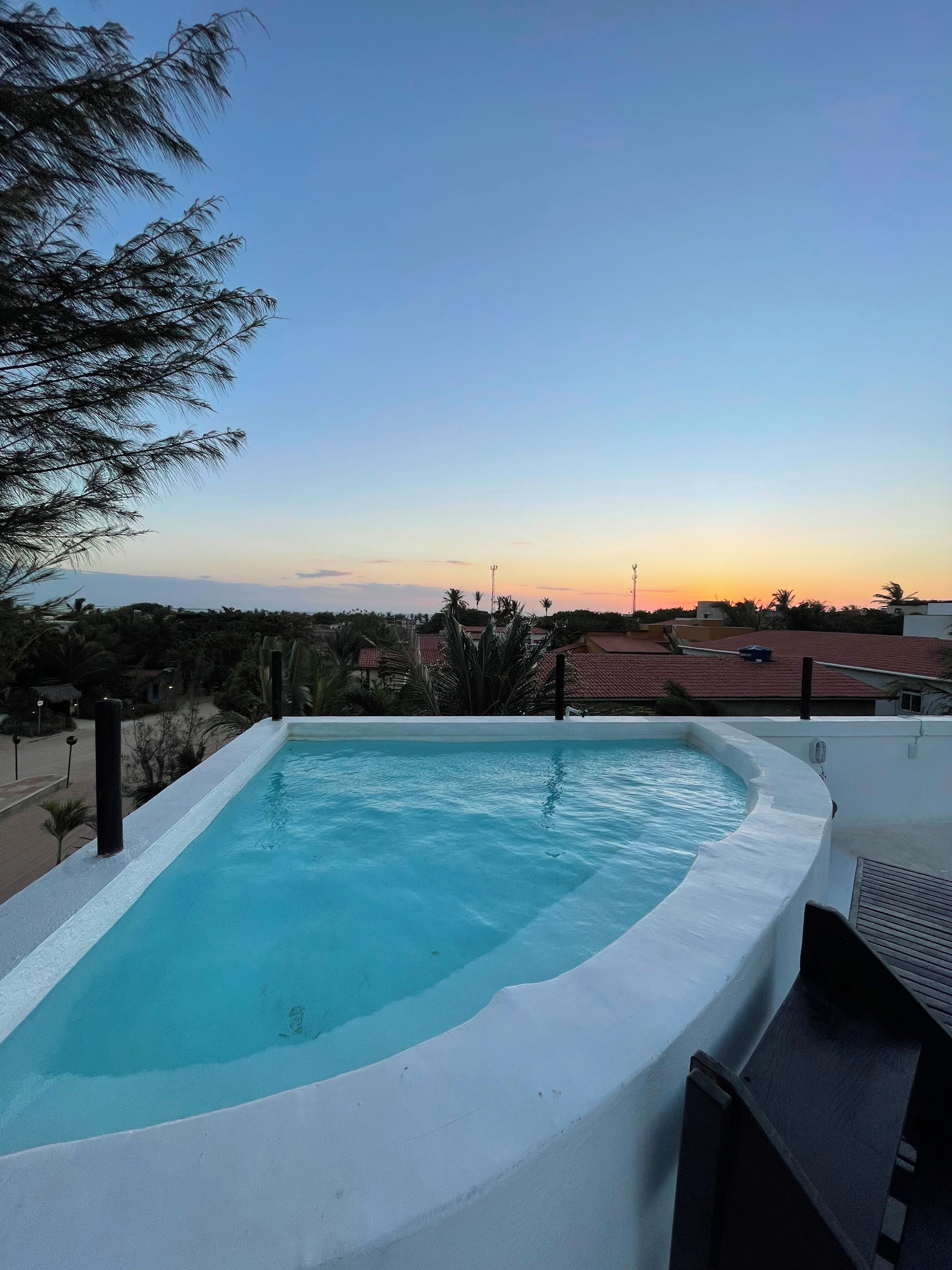 Una piscina con vistas a la puesta de sol y edificios circundantes.