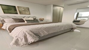 Un dormitori modern amb un llit gran, un armari i dues obres d'art penjades a la paret.