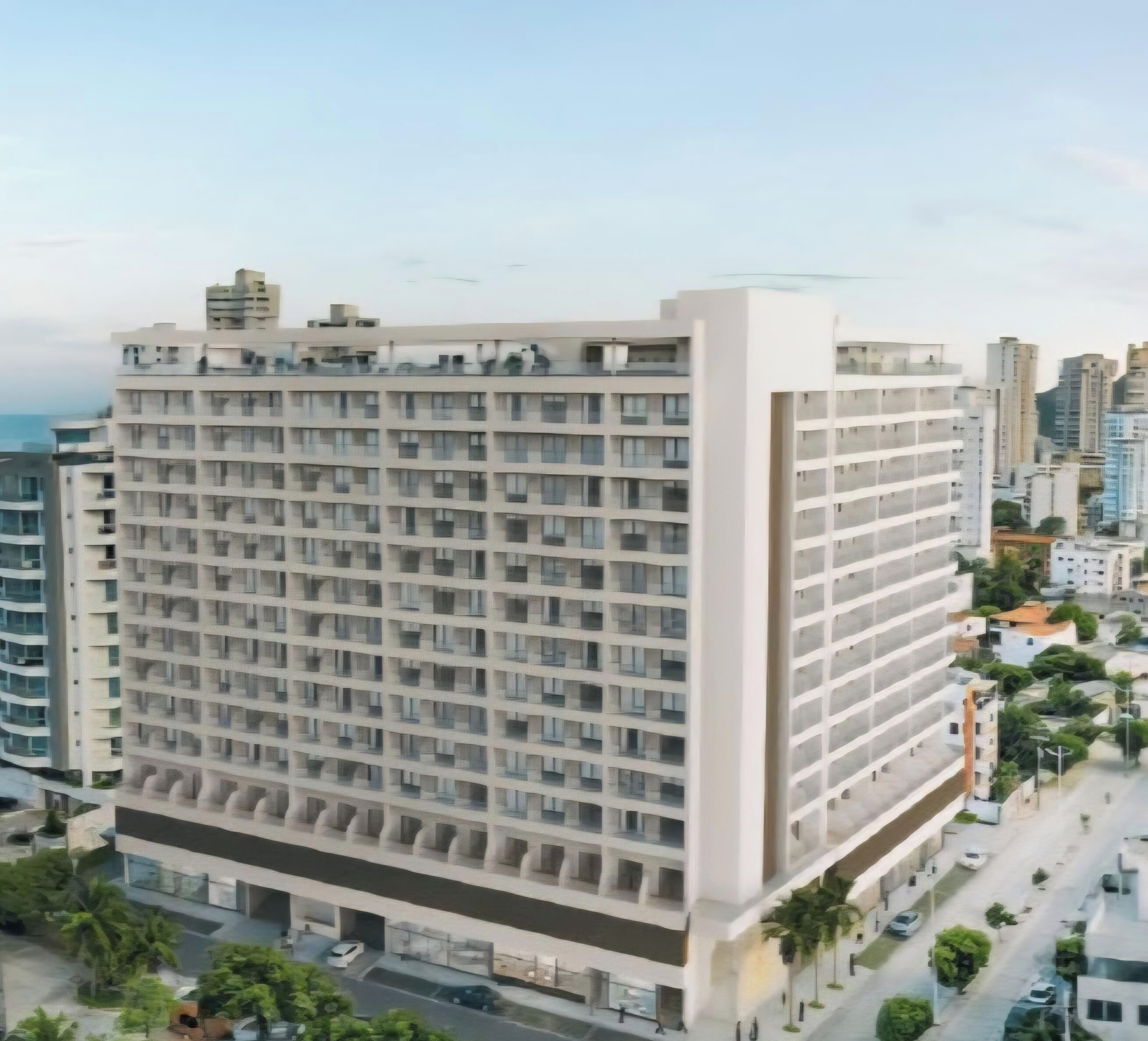 A multi-story hotel with a uniform facade, numerous balconies, and a parking area with cars.
