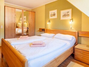 A hotel room with a double bed, wooden headboard, bedside tables, a wardrobe, and two wall-mounted lamps. - 4.5/t3 in the "freesenbruch" Holiday Park (Zingst)
