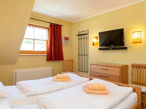 A hotel room with two beds, a television, a window with curtains, a radiator, and a wooden cabinet. - 4.5/t3 in the "freesenbruch" Holiday Park (Zingst)