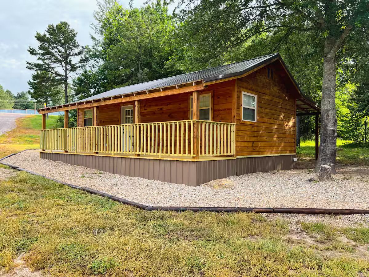 Eine Holzhütte mit überdachter Veranda und einem Schotterweg.