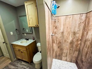 Ein Badezimmer mit einem Holzkosmetikschrank, einer Toilette und einer Duschkabine.
