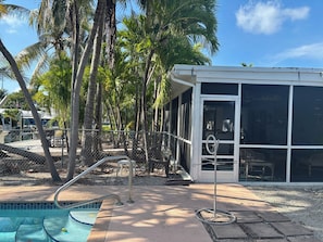 A pool area with a glass-enclosed structure, palm trees, and a clear sky.