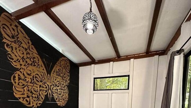 Un dormitorio con una cama de madera, un adorno en la pared y una ventana con cortinas.