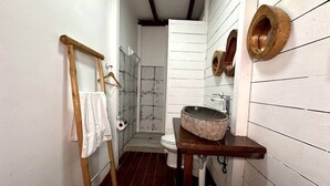 Un baño estrecho con una escalera de madera, un lavamanos blanco con cuenca de piedra y un inodoro.