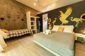 Ein Schlafzimmer mit einem großen Bett, einer kleinen Couch, einem Kleiderschrank und einer Wand mit Wandbildern.