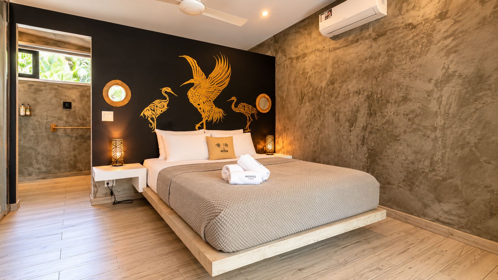 Une chambre à coucher moderne avec un grand lit, un climatiseur fixé au mur et des œuvres d’art décoratives accrochées au mur.