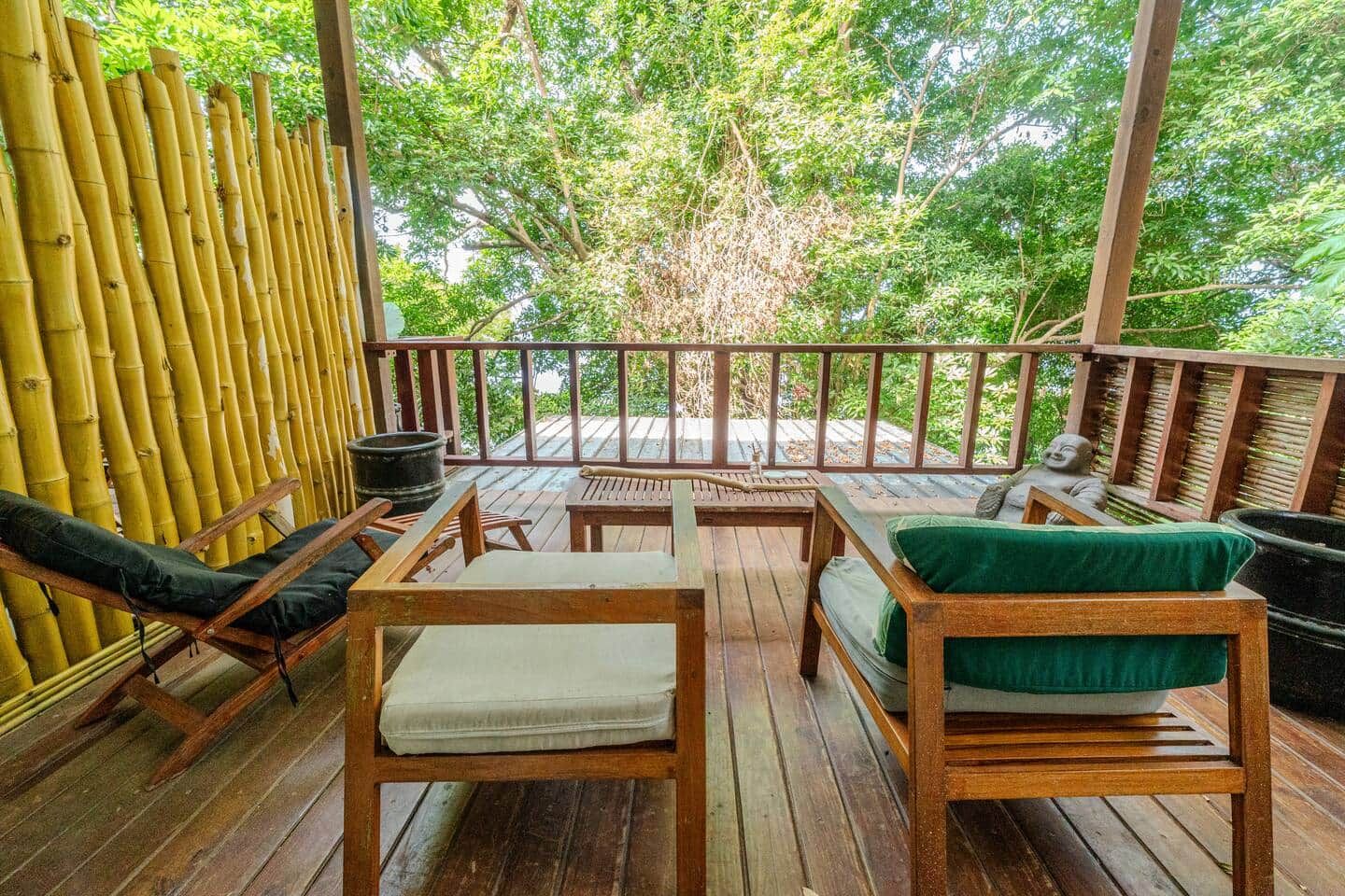 Une terrasse en bois avec des sièges et une vue sur la verdure.