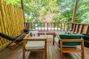 A wooden deck with seating and a view of greenery.