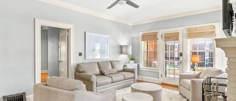 Un salon spacieux avec un plafond haut, un ventilateur de plafond, une grande fenêtre offrant une belle vue et une cheminée.