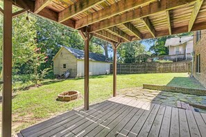 Eine Holzterrasse mit einer Pergola, einem kleinen Schuppen und einem umzäunten Garten.