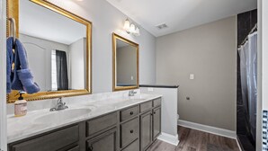 Une salle de bain avec deux lavabos, un grand miroir et un rideau de douche.