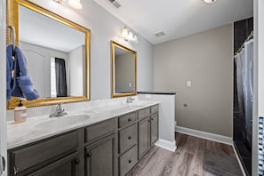A bathroom with two sinks, a large mirror, and a shower curtain. - Colonial Hills Hideaway - 2 Bedroom Home with Spacious Yard (Lillington)