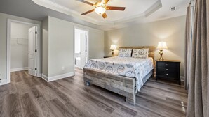 Une chambre à coucher comprenant un lit, des tables de chevet, un ventilateur de plafond et une armoire.