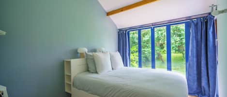Un dormitorio con cama, mesita de noche, cómoda y ventana con cortinas.