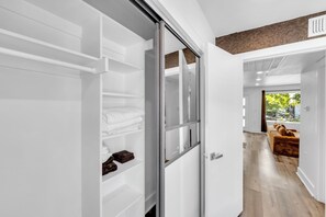 A modern interior with a sliding closet door, a wooden bench, and a view of the outdoors. - Comfy 1BR l Sleeps 4 l Near DT w/ Free Parking (Dallas)